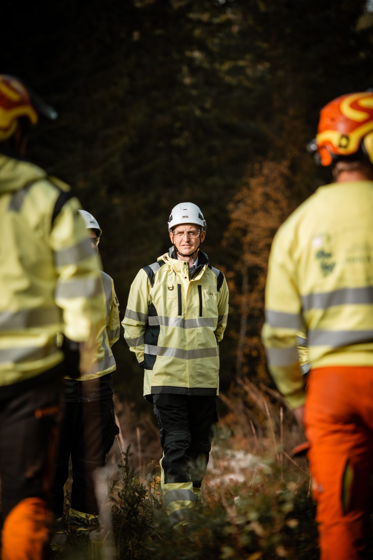 Mann i verneutstyr i samtale i skogen